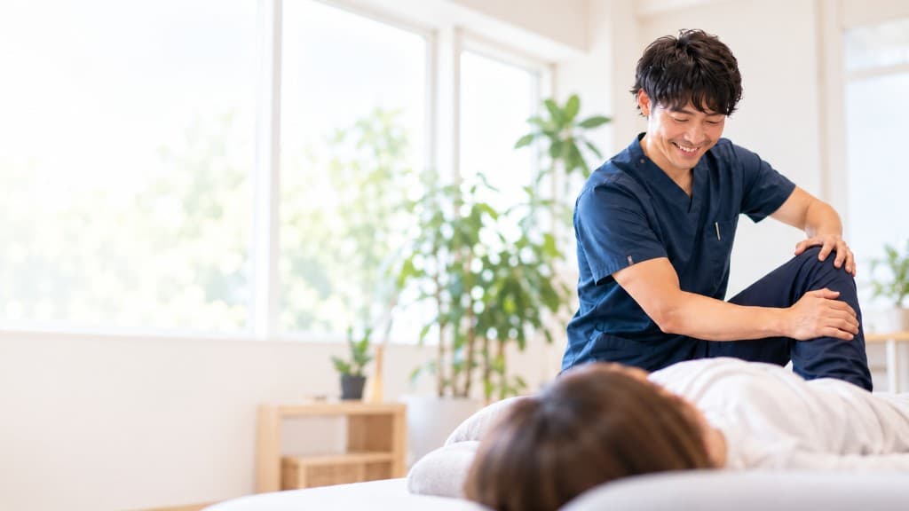 明るい部屋で患者の膝を施術する理学療法士